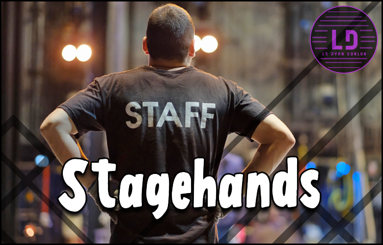 A man on stage with stagehands.